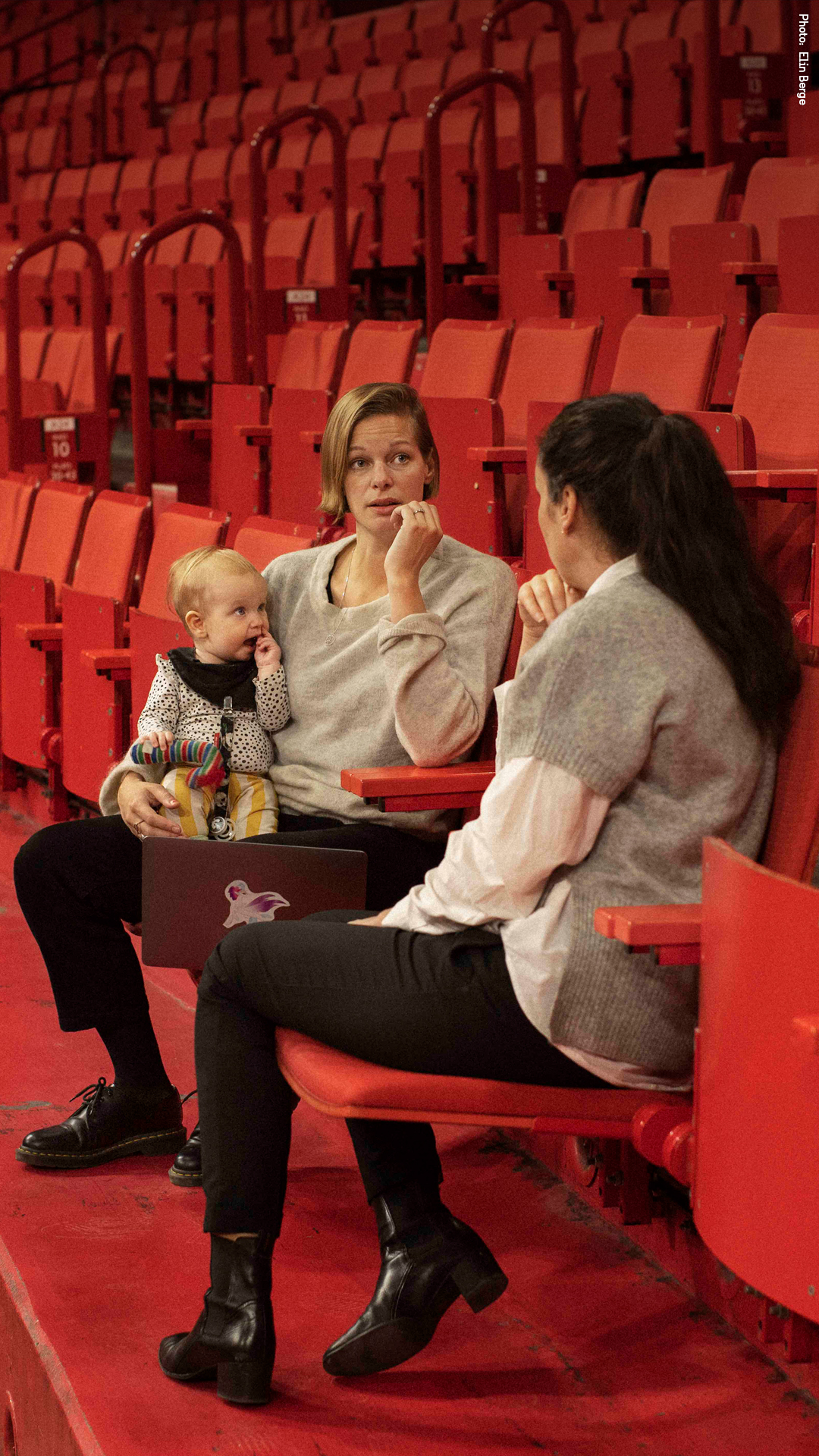 Two people having a meeting, one is holding a baby.