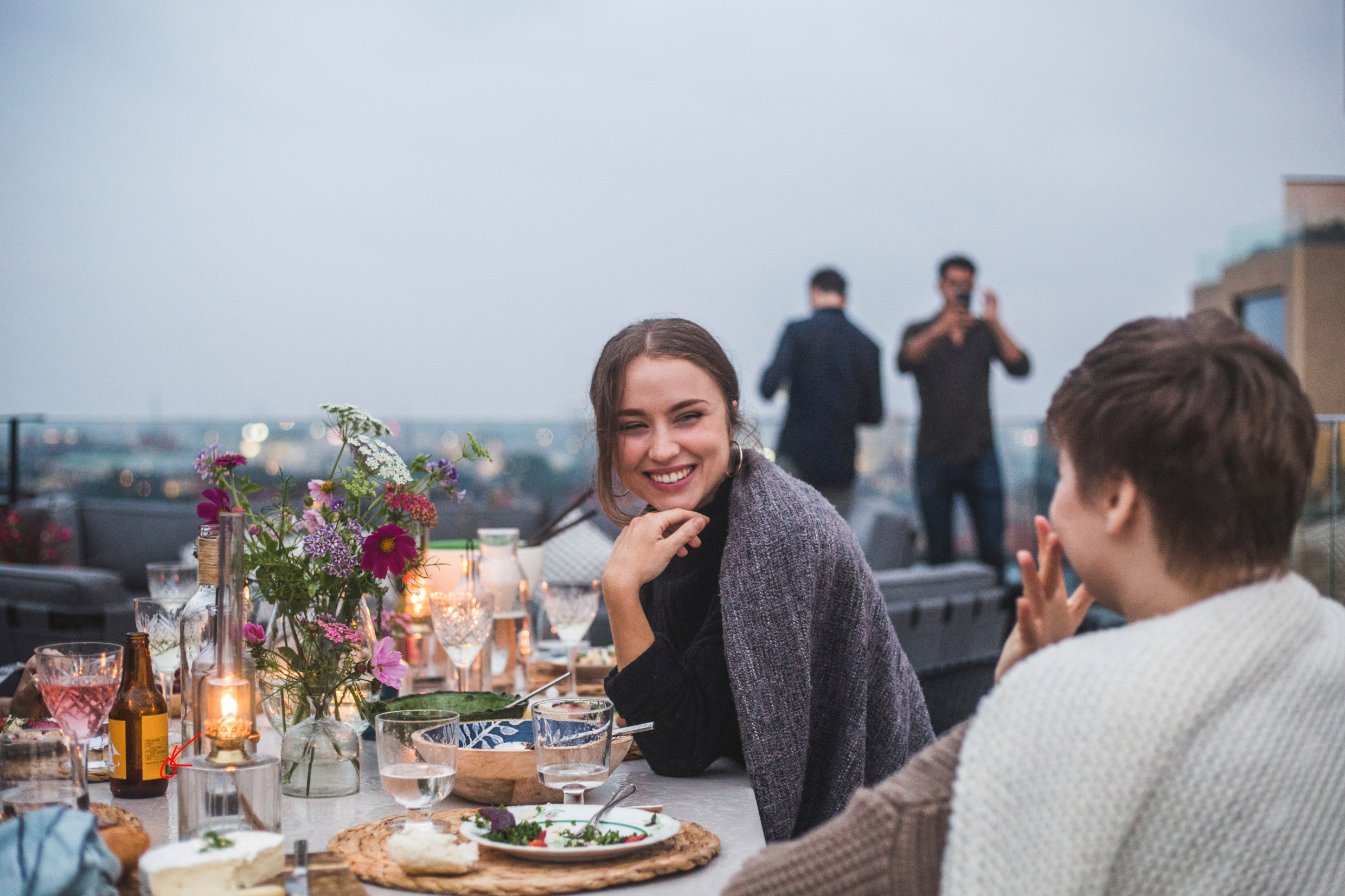 Friends eating dinner on a roof terrace in a Swedish city.