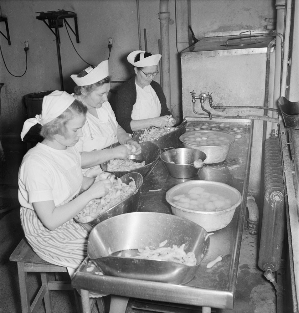 Archive photo of women peeling potatoes in a kitchen.