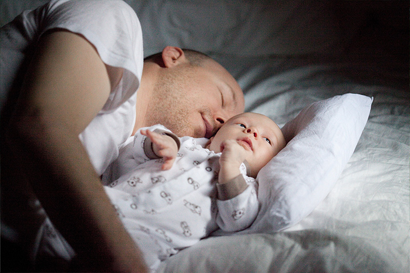 A father sleeping with his baby.