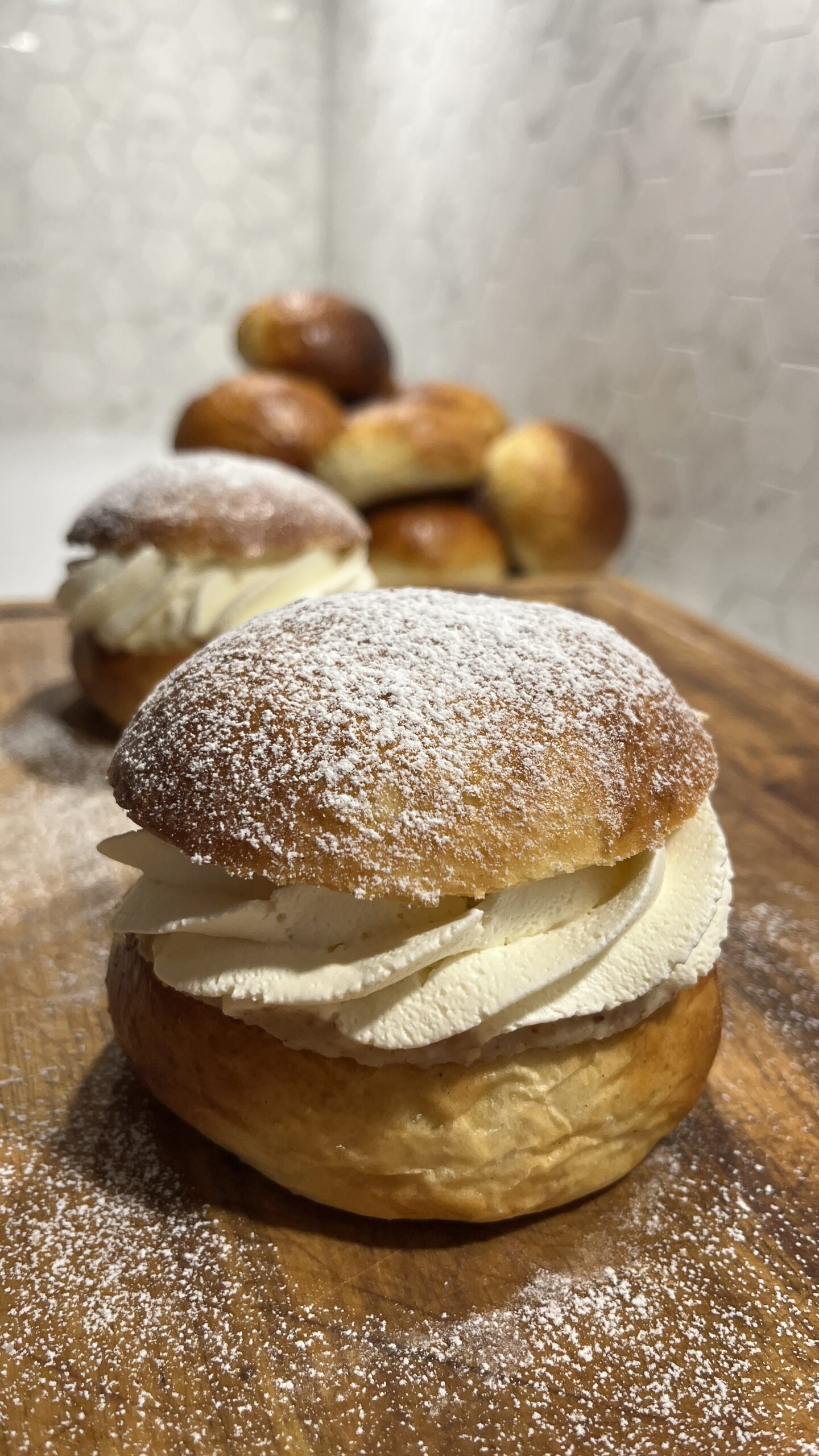 A semla with whipped cream and powdered sugar.