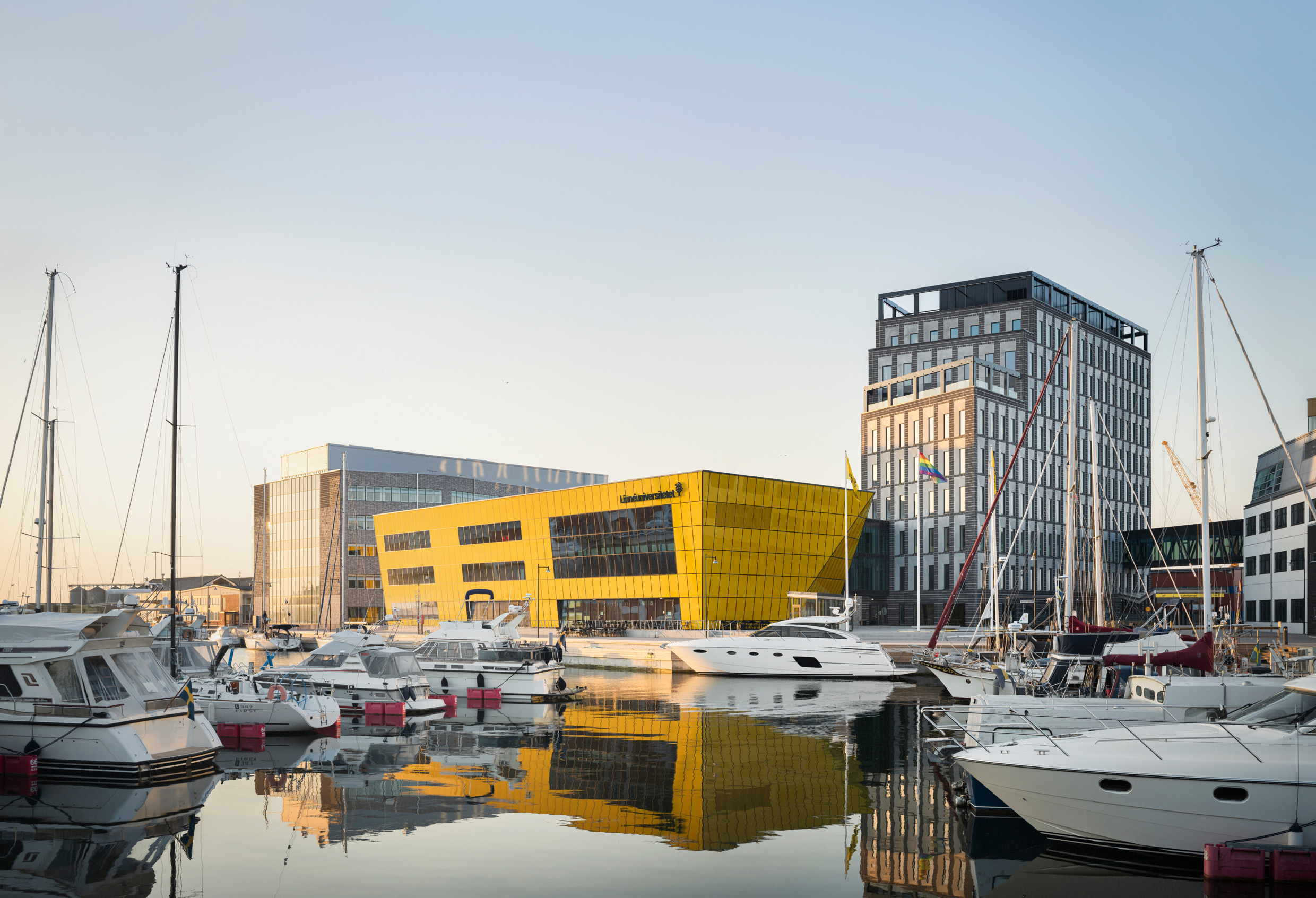 A harbour with boats fronts modern-looking large buildings.